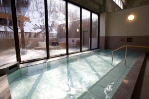 einen Pool mit Wasser in einem Zimmer mit Fenstern in der Unterkunft Yumoto Koganeyu in Jozankei
