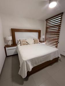 een slaapkamer met een groot bed met witte lakens en kussens bij New House Near The Beach in Ensenada