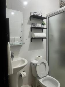 a white bathroom with a toilet and a sink at Beautiful and confortable apt in Puerto Plata +20 photos