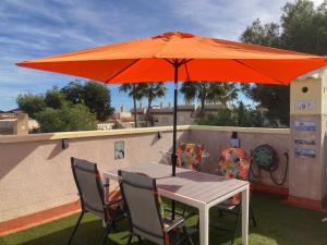 Ein Tisch und Stühle unter einem orangefarbenen Sonnenschirm auf einem Dach in der Unterkunft Casa Venetti , stylish flat in Villa Martin in Orihuela