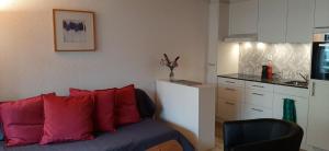 Una habitación con un sofá con almohadas rojas y una cocina. en Rothorn Center A 1Og Schöpfer, en Sörenberg