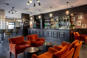 a bar with orange chairs and a bar counter at Hotel Elms Christchurch, an Ascend Collection Hotel in Christchurch