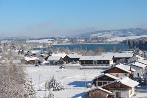a town with snow covered buildings and a lake at Morgensonne in Lechbruck