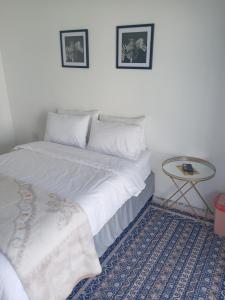 ein Schlafzimmer mit einem weißen Bett und einem kleinen Tisch in der Unterkunft M Group B&B in King Williamʼs Town