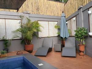 eine Terrasse mit Stühlen und Sonnenschirm und ein Pool in der Unterkunft Country Bug Private Resort in Alfonso