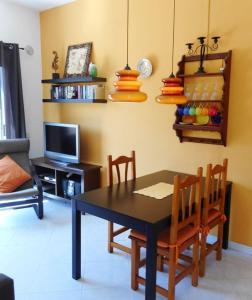 a dining room with a table and chairs and a television at Liebevoll Eingerichtetes Apartment Calima Amarilo in La Pared