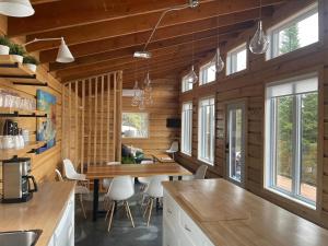a kitchen and dining room with wooden walls and windows at Chalet L'Orée Étoilée in La Tuque
