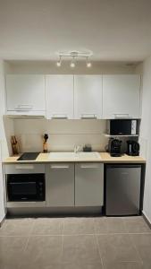 une cuisine avec des armoires blanches, un évier et une cuisinière dans l'établissement Studio Harmony with pool, à Baie Nettlé