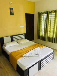 1 dormitorio con 1 cama grande y pared amarilla en Chillwind Service villa, en Padinjarathara