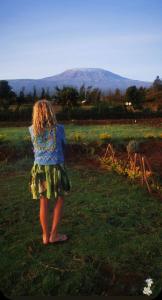 a little girl standing in a field of grass at Amboseli Trails Cabin in Amboseli