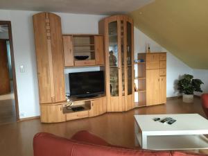 sala de estar con armarios de madera y TV de pantalla plana en Ferienwohnung Villringer, en Orschweier