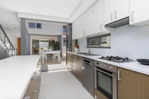 cocina con encimeras blancas y fogones en Welcome to Cottesloe Beach!, en Perth