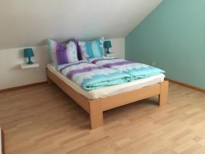 ein Schlafzimmer mit einem Bett mit lila und blauen Kissen in der Unterkunft Ferienwohnung Villringer in Orschweier