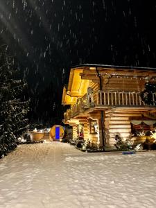 eine Blockhütte im Schnee bei Nacht in der Unterkunft The Mountain's Sea Chalet in Colibiţa