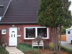 a red brick house with a white door and a bench at Daisy 78 in Wilhelmshaven +4 photos