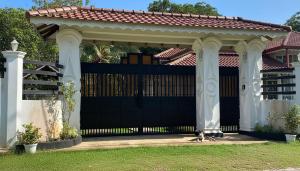 a black gate with a dog sitting under it at Silva Villa Negombo in Negombo