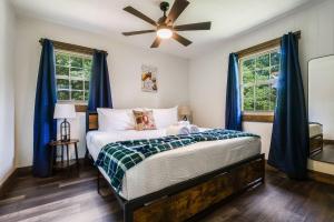 Schlafzimmer mit einem Bett mit blauen Vorhängen und einem Deckenventilator in der Unterkunft Fox&Hound Cabin: Cold Plunge, Sauna, Hot Tub, Dogs in Basye