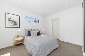 Un dormitorio blanco con una cama y una mesa. en Welcome to Cottesloe Beach!, en Perth