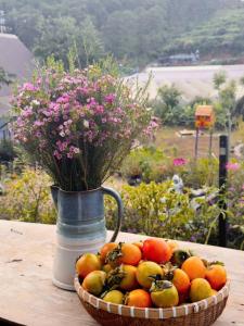 un panier de fruits sur une table avec un vase de fleurs dans l'établissement Nhà Của Thùy, à Ấp Lat