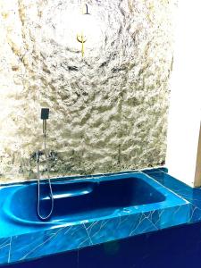 La salle de bains est pourvue d'une baignoire bleue et d'un mur en pierre. dans l'établissement Sana Villa & Resort Goa, à Anjuna