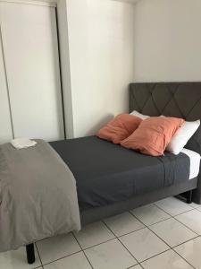 Una cama con dos almohadas encima en una habitación. en L'Échappée Bleue Studio à 5 min du port et plage, en Saint-Gilles-les-Bains