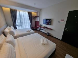 Una habitación de hotel con dos camas y un televisor. en Miico Hotel Permas Jaya, en Johor Bahru