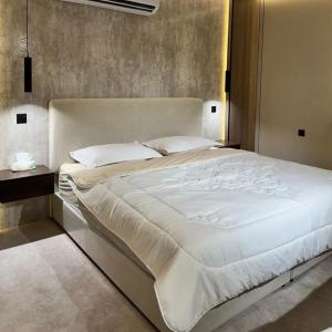 1 cama blanca grande en un dormitorio con pared en Afandina Hotel, en Kuwait