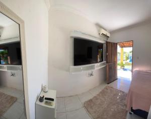 a room with a tv and a bed and a mirror at Casa Amarela Caponga in Cascavel