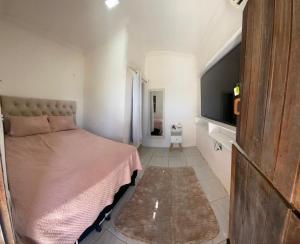 a bedroom with a bed and a flat screen tv at Casa Amarela Caponga in Cascavel