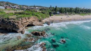 an aerial view of a beach with rocks and the ocean at Kove Caves Beach in Caves Beach