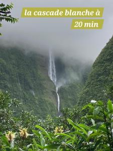 une cascade dans les montagnes avec les mots la cascade blanche à min dans l'établissement Appartement vue mer, à Saint-Denis