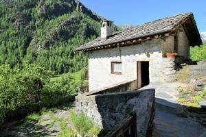 ein kleines Steingebäude mit einer Tür auf einem Berg in der Unterkunft Stone Mountain Cabin Overlooking Ala Valley in Alo di Stura