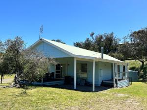a white house with a porch on a field at Famlee Ties in Venus Bay