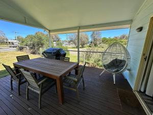 a porch with a wooden table and chairs and a swing at Famlee Ties in Venus Bay +16 photos