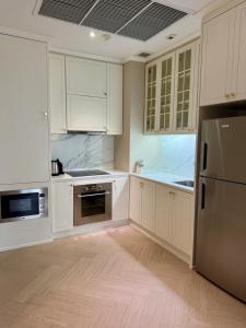 a kitchen with white cabinets and a stainless steel refrigerator at Rongratana Executive Residence Bangkok in Bangkok
