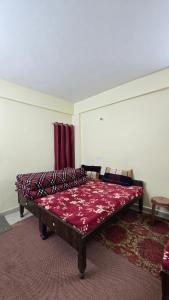 a bed sitting in a room with a red blanket at Shivpuri House Kedarnath in Kedārnāth
