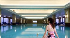 eine Frau in einem Kleid sitzt vor einem Swimmingpool in der Unterkunft Changzhou Fudu Qingfeng Garden Hotel in Changzhou