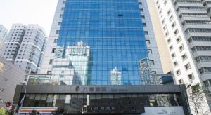 a large glass building in a city with buildings at Urumqi Bayinhe Hotel in Ürümqi