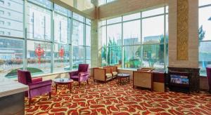 eine Lobby mit lila Stühlen und ein Zimmer mit Fenstern in der Unterkunft Qingdao Chengyang Detai Hotel in Qingdao