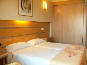 two beds in a hotel room with towels on them at Hostal la Savina in La Savina