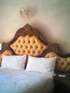 Bett mit einem Kopfteil aus Holz und weißen Kissen in der Unterkunft Mooka in Pyramid