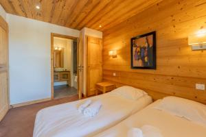 two beds in a room with wooden walls at l'Ours Bleu C21 - Ski In Ski Out - Happy Rentals in Vallorcine