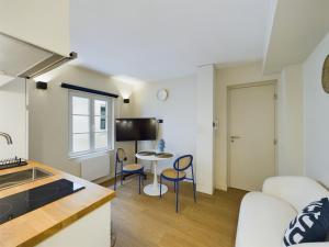 eine Küche und ein Wohnzimmer mit einer Couch und einem Tisch in der Unterkunft Charmant 2 pièces très calme aux pieds de la Cathédrale in Straßburg