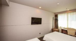 a bedroom with two beds and a tv on the wall at Jinjiang Inn Style Shijiazhuang Zhongshan Xi Road Yuxi Park in Shijiazhuang