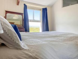 a bedroom with a large bed with a large window at Downhouse in Delabole