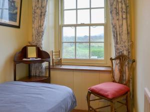 a bedroom with a bed and a window and a chair at Downhouse in Delabole +25 photos