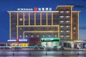 a large building with cars parked in front of it at Borrman Hotel Zhongxiang Railway Station Mochou Village in Zhongxiang