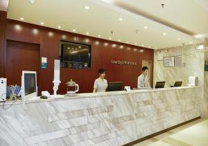 zwei Personen stehen an einer Rezeption in einer Lobby in der Unterkunft City Comfort Inn Guangzhou Luyuan Road Taojin Metro Station in Guangzhou