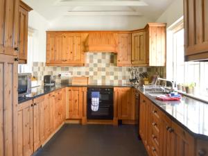 a kitchen with wooden cabinets and a black dishwasher at Breasty Haw in Grizedale