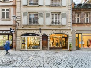 Eine Frau, die an einem Gebäude mit Lagerfronten vorbeigeht. in der Unterkunft Charmant 2 pièces très calme aux pieds de la Cathédrale in Straßburg